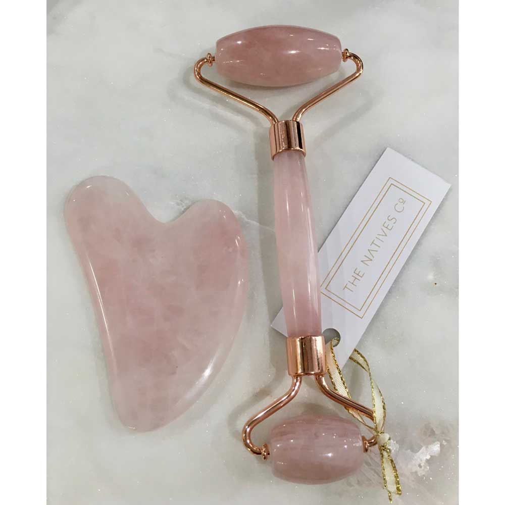 rose quartz crystal facial roller gua sha on marble